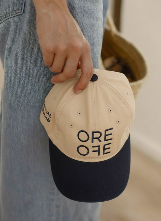 Person holding a cap with 'ORE OFE' text in a casual setting