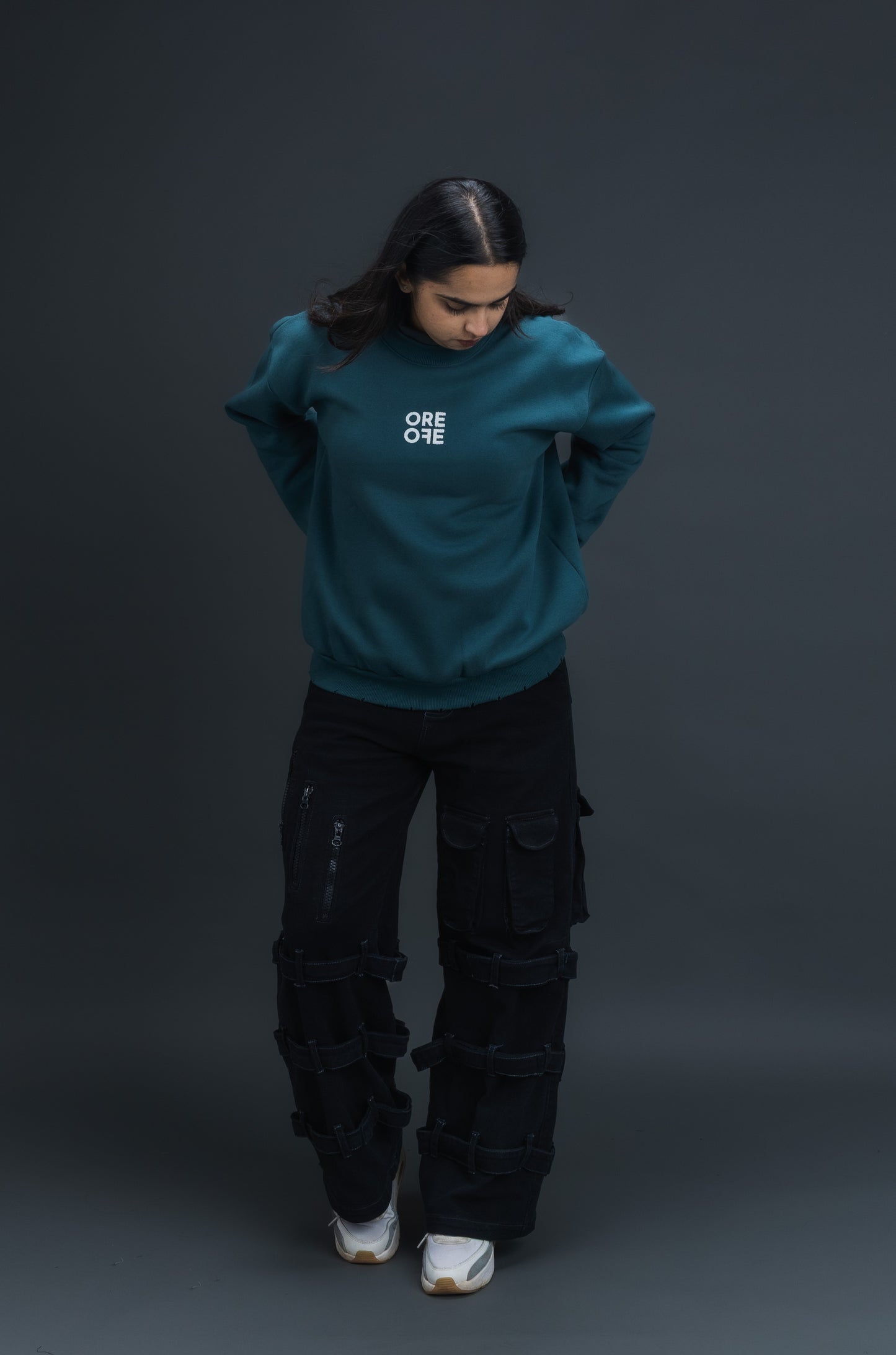 Person wearing a teal sweater with ORE OFE logo on the centre of the chest